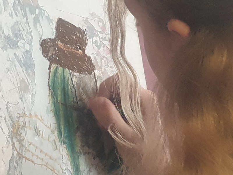 Enfant en train de colorier un dessin mural représentant un cactus aux couleurs vives avec des pastels.